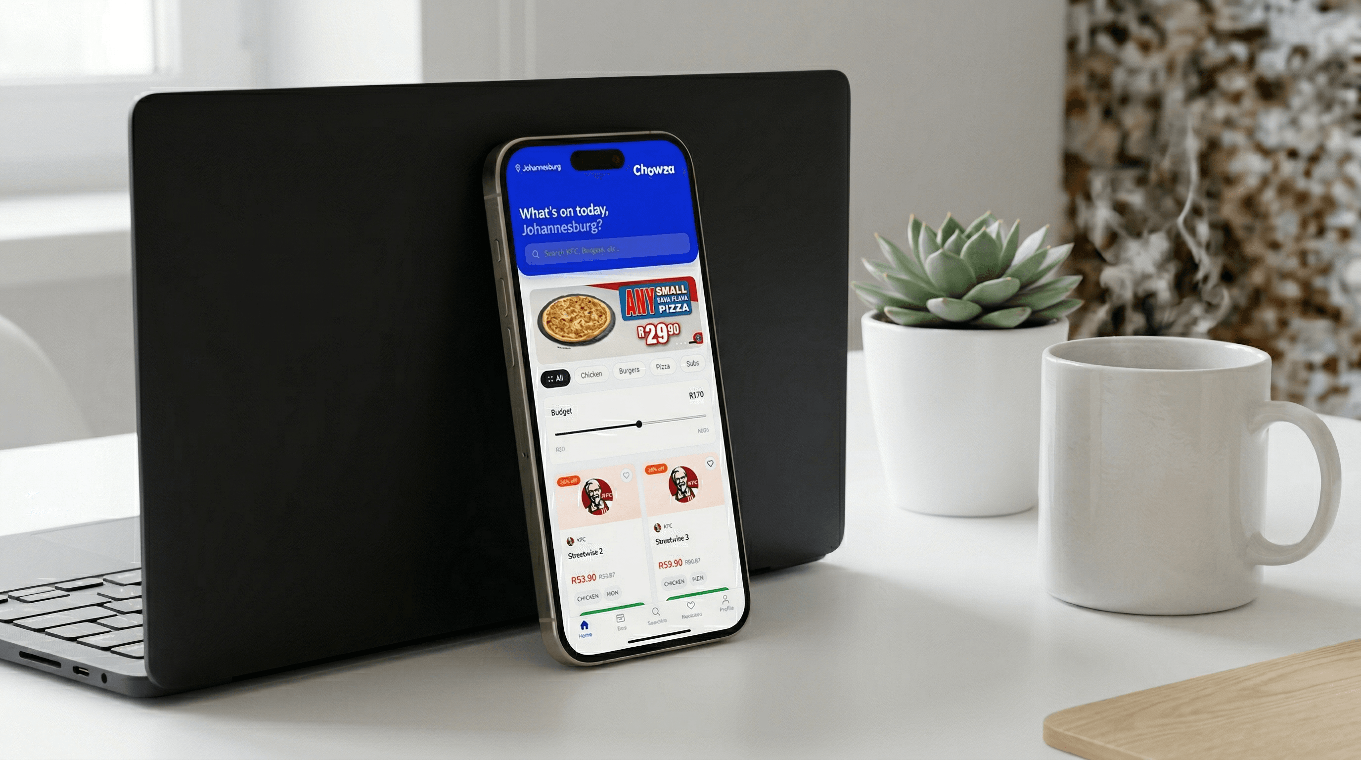 An app open on a phone beside a laptop